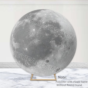 May include: A large, round backdrop featuring a detailed depiction of the moon's surface in shades of gray. The backdrop is supported by a gold-colored stand. The text "KEYIFADESIGN" is printed across the surface. The backdrop is made of polyester with an elastic band.
