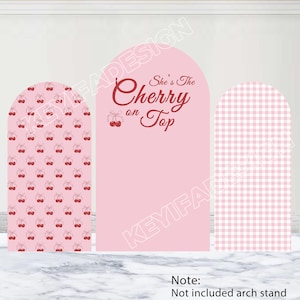 Op de afbeelding: Drie roze boogvormige panelen. Het linkerpaneel heeft een herhalend patroon van rode kersen op een roze achtergrond. Het middelste paneel is effen roze met de tekst "She's The Cherry on Top" in rood script. Het rechterpaneel heeft een roze en wit geruit patroon.