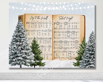 May include: An image of an open book with the lyrics to the Christmas carols "Joy to the World" and "Silent Night". The book is surrounded by two small snow-covered pine trees.