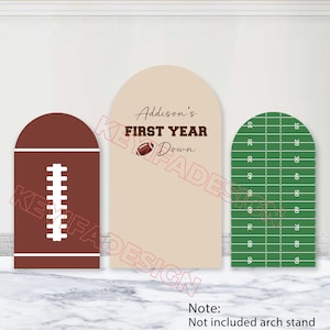 May include: Three arched display panels featuring a football theme. The left panel is brown with white laces. The center panel is beige with the text Addison's FIRST YEAR Down and a football graphic. The right panel is a green football field.