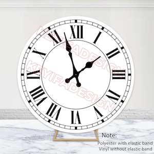 May include: A large, round clock face with black Roman numerals against a white background. The clock hands are black, indicating the time. The clock is supported by a wooden frame. The text "KEYIFADESIGN" is watermarked across the clock face.