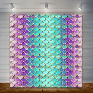 May include: A backdrop featuring a mermaid scale pattern in shades of turquoise, purple, and pink with gold glitter accents.