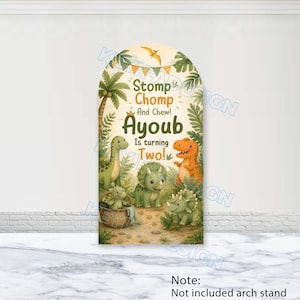 Op de afbeelding: Een boogvormige achtergrondhoes met een junglethema met palmbomen en diverse dinosaurussen. De tekst luidt Stomp Chomp And Chew! Ayoub is turning Two! met een klein kroonicoontje. Het ontwerp bevat een mandje met een babydinosaurus erin.