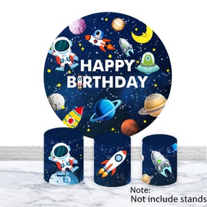 May include: A set of three round backdrop decorations for a birthday party. The backdrop is a blue and black space theme with stars, planets, rockets, and astronauts. The text "Happy Birthday" is printed in white on the largest backdrop.