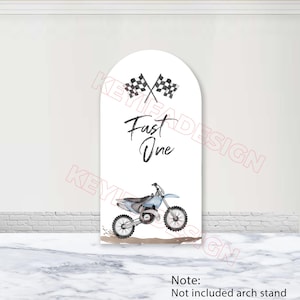 May include: White arch-shaped sign with a light blue dirt bike illustration. The sign features the text "Fast One" in black script, along with two checkered flags. The bottom of the sign has a note that says "Not included arch stand".