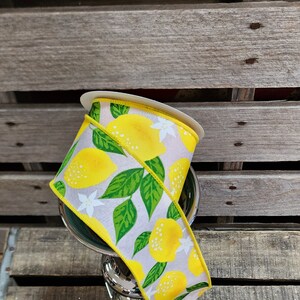 May include: A roll of yellow and white ribbon with a lemon print. The ribbon is on a wooden surface.