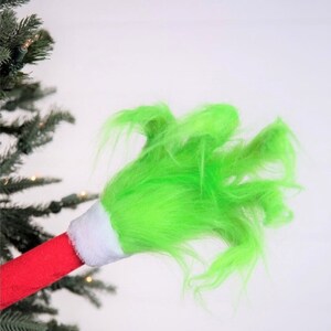 May include: A green fuzzy Christmas tree topper with a red and white base.