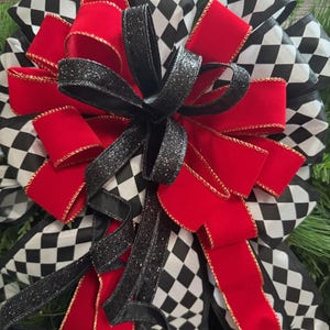 Puede incluir: Un lazo decorativo con cintas rojas, negras y blancas. El dise&ntilde;o incluye cintas rojas lisas con ribete dorado, cintas negras con purpurina y cintas con un patr&oacute;n de cuadros blanco y negro. Ideal para decoraciones de temporada o festivas.