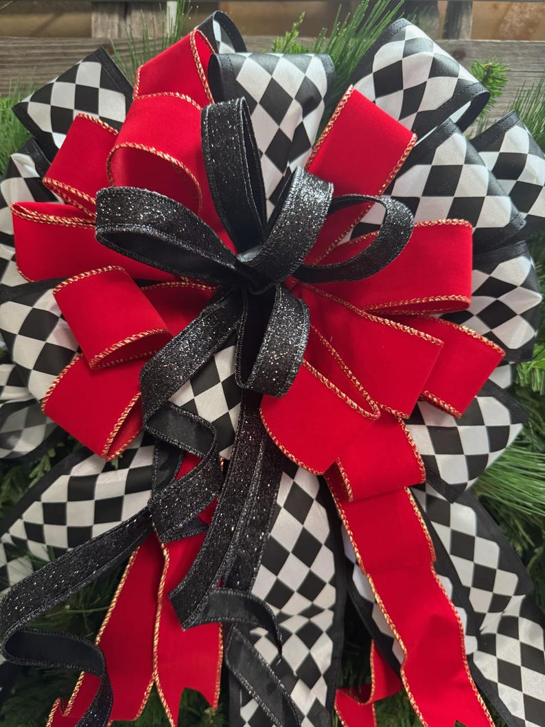 Puede incluir: Un lazo decorativo con cintas rojas, negras y blancas. El dise&ntilde;o incluye cintas rojas lisas con ribete dorado, cintas negras con purpurina y cintas con un patr&oacute;n de cuadros blanco y negro. Ideal para decoraciones de temporada o festivas.