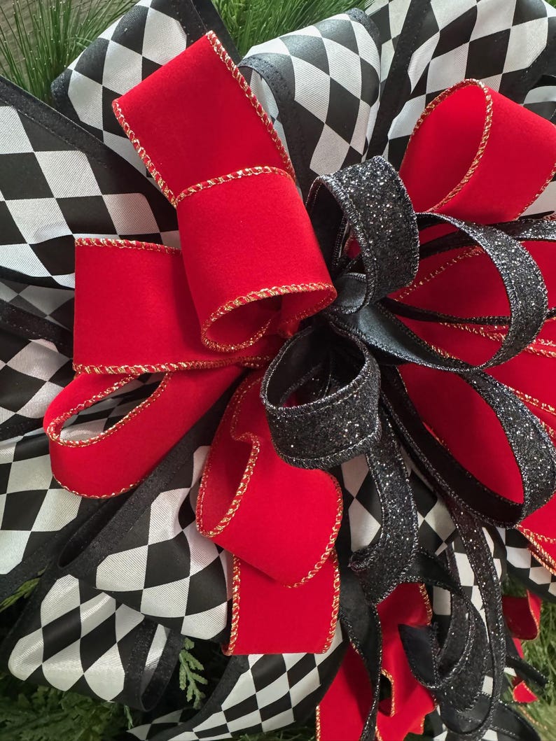 Puede incluir: Primer plano de un lazo decorativo con cinta de terciopelo roja con ribete dorado, cinta negra con purpurina y cinta a cuadros blancos y negros. El lazo es probablemente para una corona u otra decoraci&oacute;n navide&ntilde;a.