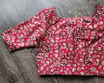 May include: A pink blouse with a floral print. The blouse has a square neckline and three-quarter sleeves. The fabric is a cotton blend.