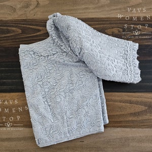 May include: A light gray embroidered fabric with a floral pattern. The fabric is folded in half and has a Vavs Womens Stop label with the text "Six Yards of Grandeur".