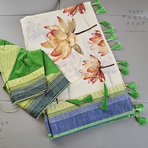 Op de afbeelding: Een crèmekleurig textiel met grote bloempatronen in tinten oranje en bruin. De rand heeft blauwe en groene strepen, geaccentueerd met groene kwastjes. Er is ook een apart groen kledingstuk aanwezig.