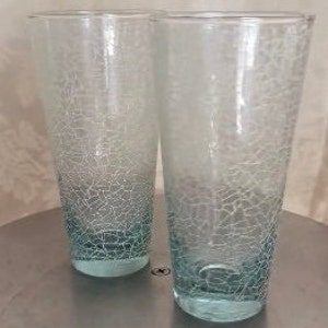 May include: Two tall, clear glass drinking glasses with a light blue crackle finish.