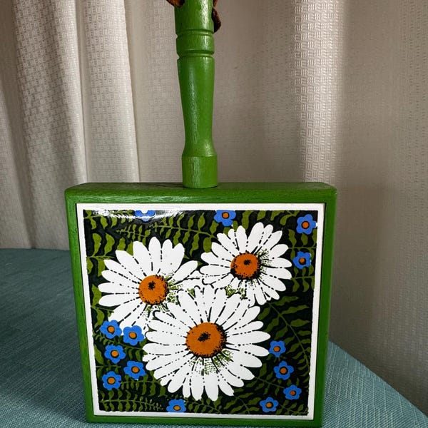 VTG 1970’s  lime green wooden trivet with a ceramic tile in the middle picturing a floral design of 3 white daisies and little blue flowers