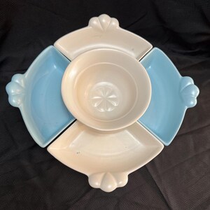 May include: A vintage serving dish set with a central bowl and four surrounding dishes. The set features a light blue and cream color scheme. Each dish has a decorative, scalloped edge. The central bowl has a starburst design.