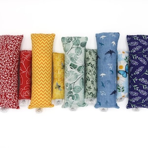 May include: A set of eight colourful fabric catnip toys. The toys are rectangular and feature different patterns, including floral, geometric, and animal prints.
