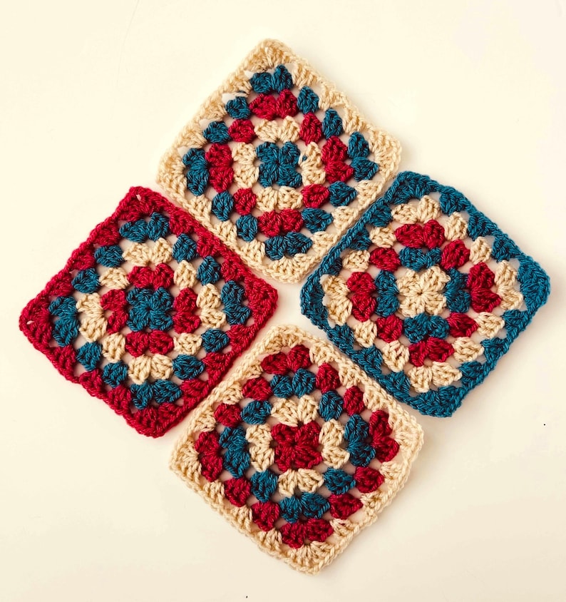 May include: Four crocheted granny squares in shades of cream, teal, and red. Each square features a central circle design.