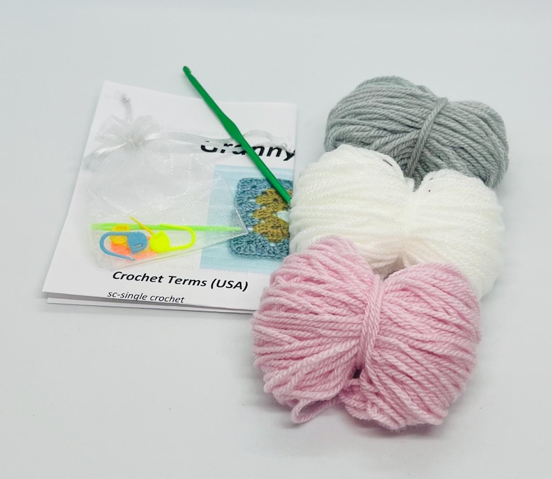 May include: A crochet kit with three balls of yarn in pink, white, and gray, a crochet hook, and instructions. The instructions include the term "sc-single crochet".
