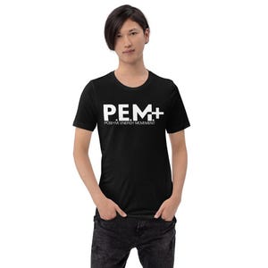 May include: Black t-shirt with the white text "P.E.M.+" and "POSITIVE ENERGY MOVEMENT". The shirt is short-sleeved and has a crew neck. The model is wearing dark jeans.