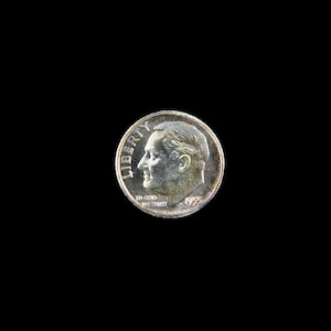 May include: A silver US dime coin with the profile of President Franklin D. Roosevelt on the obverse. The coin reads "LIBERTY" and "IN GOD WE TRUST" and is dated "1955".