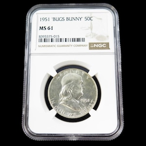 Puede incluir: Una moneda de plata de 1951, calificada MS 61, con un retrato y la inscripción "IN GOD WE TRUST". La moneda está en un soporte protector transparente, con el texto "1951 'BUGS BUNNY' 50C" y "NUMISMATIC GUARANTY COMPANY".