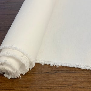 以下が含まれることがあります： フリンジの付いた白いキャンバスロール。キャンバスは巻かれており、端が見えています。