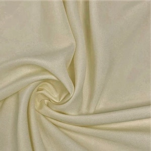 May include: Cream colored fabric with a smooth texture. The fabric is draped and folded, showing its soft and flowing nature.