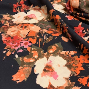 May include: Black fabric with a floral print featuring orange, pink, and white flowers. The fabric has a soft, flowing texture.