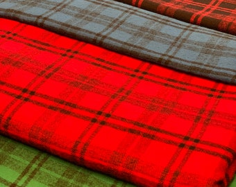 May include: Four different plaid fabrics stacked on top of each other. The top fabric is red and black, the second is blue and black, the third is red and black, and the bottom is green and black.