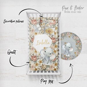 Puede incluir: Un juego de ropa de cama para cuna de beb&eacute; con estampado floral que presenta un elefante gris y el nombre "Isabella". El juego incluye una colcha, una alfombra de juego y almohadas decorativas.