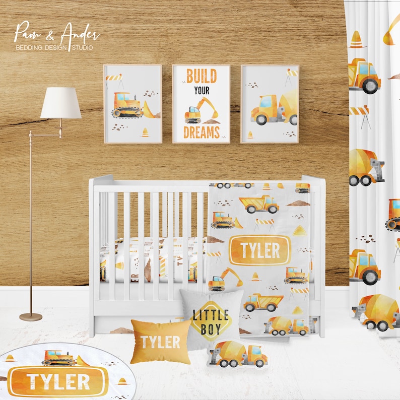 May include: A nursery room decorated with a construction theme. The room features a white crib with a yellow and gray construction vehicle themed bedding set, a yellow and gray round rug with a construction vehicle, a yellow and gray pillow with the text "Little Boy", a yellow and gray pillow with the text "Tyler", and three framed prints with construction vehicles and the text "Build Your Dreams".