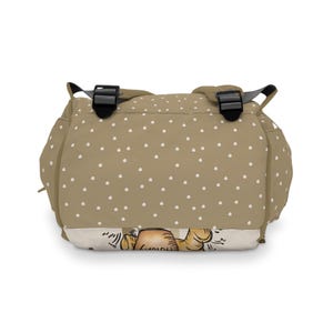 May include: A tan polka dot backpack with adjustable straps. The backpack has a cartoon illustration of a bear on the bottom.