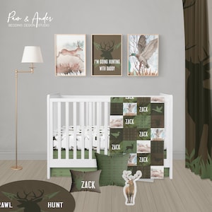 Puede incluir: Una habitación de bebé decorada con un tema de bosque con una cuna blanca, ropa de cama verde y marrón y tres impresiones enmarcadas con ciervos y patos. Las impresiones incluyen el texto "Voy a cazar con papá".