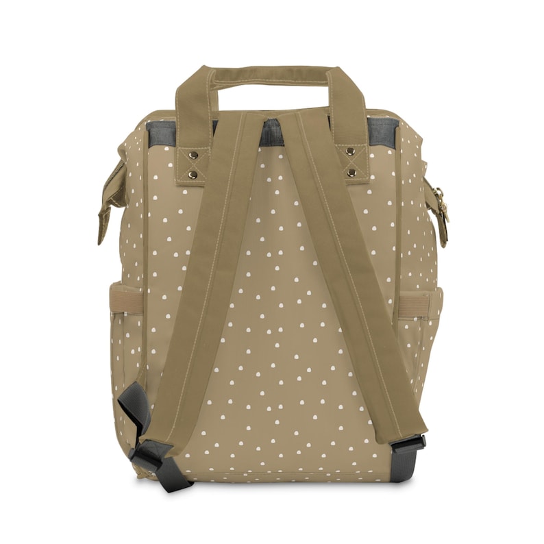 May include: A tan canvas backpack with white polka dots and adjustable straps. The backpack has a top handle and a zippered closure.