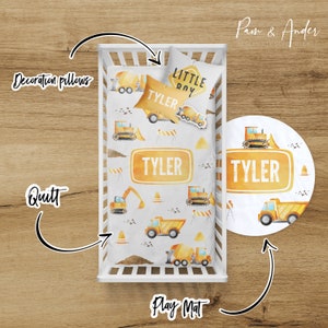 May include: A white crib with a yellow and white construction themed bedding set. The bedding includes a quilt, a pillow, and a play mat. The quilt and pillow feature a watercolor design of construction vehicles, including a dump truck, a bulldozer, and a cement mixer. The play mat is a round, yellow and white mat with a similar design. The bedding is personalized with the name "Tyler" and the phrase "Little Roy".