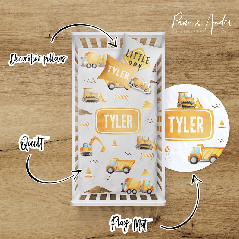 May include: A white crib with a yellow and white construction themed bedding set. The bedding includes a quilt, a pillow, and a play mat. The quilt and pillow feature a watercolor design of construction vehicles, including a dump truck, a bulldozer, and a cement mixer. The play mat is a round, yellow and white mat with a similar design. The bedding is personalized with the name "Tyler" and the phrase "Little Roy".