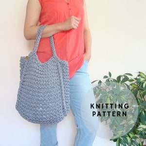 May include: A grey knitted tote bag with leather handles. The bag is being held by a person wearing a red shirt and blue jeans. The text "KNITTING PATTERN" is visible in the image.