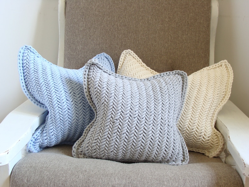May include: Three knitted throw pillows in a chevron pattern. The pillows are light blue, gray, and cream.