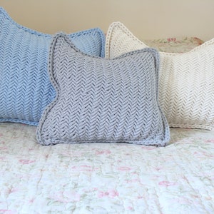 May include: Three decorative throw pillows with a herringbone pattern. The pillows are in shades of light blue, gray, and white.