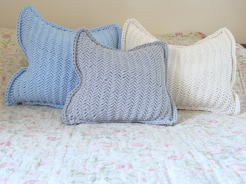 May include: Three decorative throw pillows with a herringbone pattern. The pillows are in shades of light blue, gray, and white.