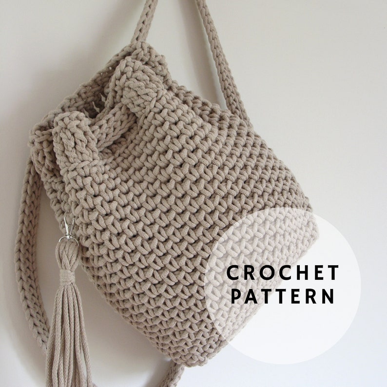 May include: A beige crocheted backpack with a drawstring closure and a tassel. The backpack has adjustable straps and is made with a chunky yarn. The image includes the text "CROCHET PATTERN".