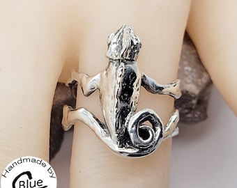 Könnte beinhalten: Silberring mit einem detaillierten Chamäleon-Design. Das Chamäleon ist mit seinem Schwanz um seinen Körper gewickelt zusammengerollt. Der Ring ist handgefertigt von Blue MakoshopStore.