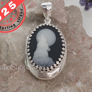 May include: A silver locket with a black and white cameo of a wolf howling at the moon. The locket has a detailed filigree design around the edge.