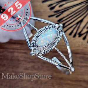 Peut inclure: Un bracelet en argent avec une pierre d'opale blanche sertie dans un cadre en argent détaillé. Le bracelet présente un délicat motif de corde sur les côtés.