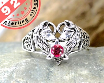 May include: Sterling silver ring featuring two wolf heads facing each other, forming a heart shape. The ring has a red gemstone in the center.