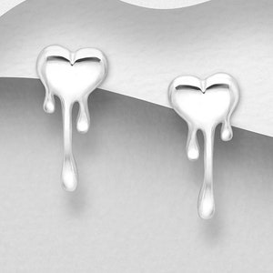May include: A pair of silver heart-shaped earrings with a dripping effect. The earrings are made of metal and have a shiny finish.