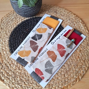 Könnte beinhalten: Zwei Stoff-Bleistiftetuis mit einem Ginkgoblatt-Muster. Die Etuis werden von "Crealine Fabrique" hergestellt und sind mit "Etui à crayon pour livre" beschriftet.