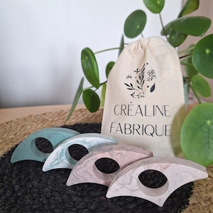 Peut inclure: Trois porte-bagues faits à la main en résine marbrée. Les porte-bagues sont dans des tons de vert et de rose. Les porte-bagues sont emballés dans un sac en mousseline blanche avec le texte "Créaline Fabrique" imprimé dessus.