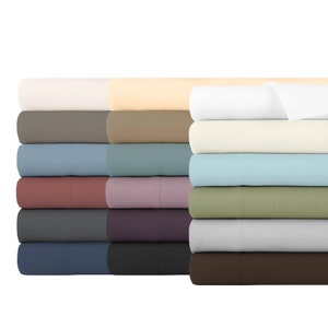 May include: A stack of folded fabric sheets in various solid colors including white, cream, light blue, sage green, gray, dark brown, navy, charcoal, mauve, dusty rose, teal, taupe, and beige, arranged in a neat, organized vertical pile.